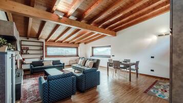 Una sala moderna con techo de madera, un conjunto de sofás, una mesa de comedor y una zona de cocina.