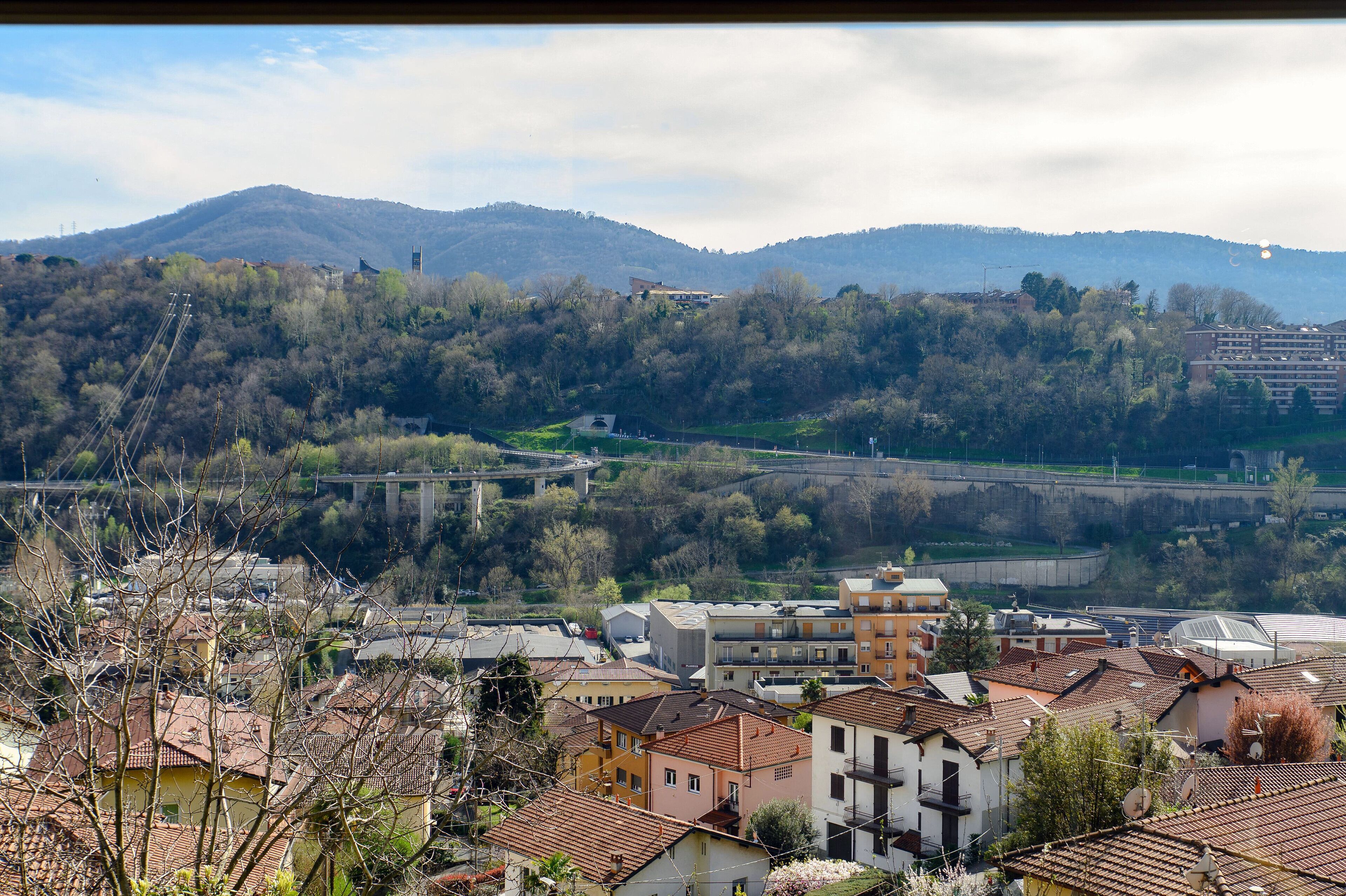 A town with buildings, a bridge, and hills in the background.
