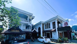 A two-story building with a guesthouse on the ground floor, a balcony, and a parked car. - Walking Street Hotel (Vang Vieng)