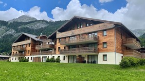 A two-story wooden chalet with balconies, set against a mountainous backdrop. - Apartment in La Chapelle Near Ski Lift (La Chapelle-d'Abondance)