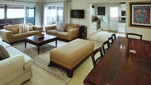 A spacious living room with a large wooden dining table, two sofas, and a flat-screen TV. - Klopdisselboom Langebaan 10-sleeper (Langebaan)