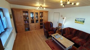 Uma sala de estar aconchegante com piso de madeira, um sofá, uma mesa de centro e uma estante de livros.