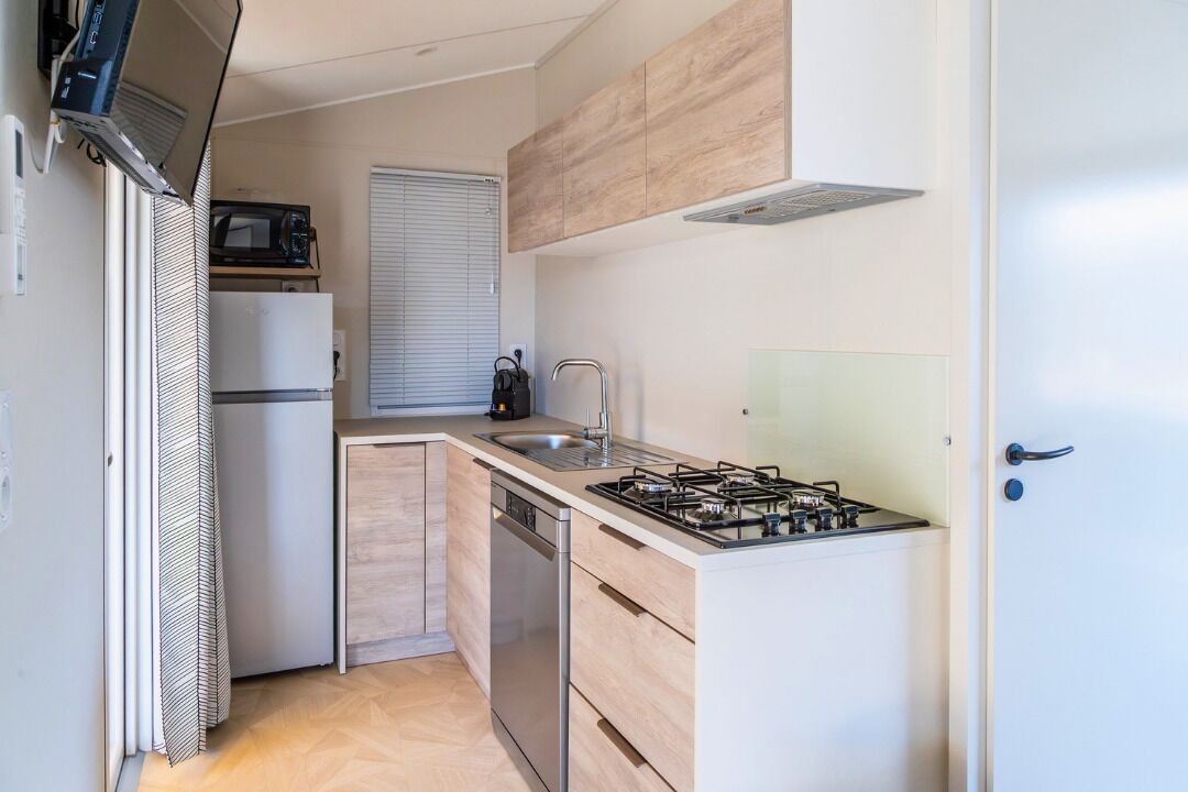 Une cuisine de taille réduite équipée d’une cuisinière à gaz, d’un évier et d’un four à micro-ondes.