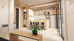 Un intérieur moderne avec des poutres apparentes, une table centrale agrémentée d’une plante en pot et un coin cuisine avec des tabourets de bar.