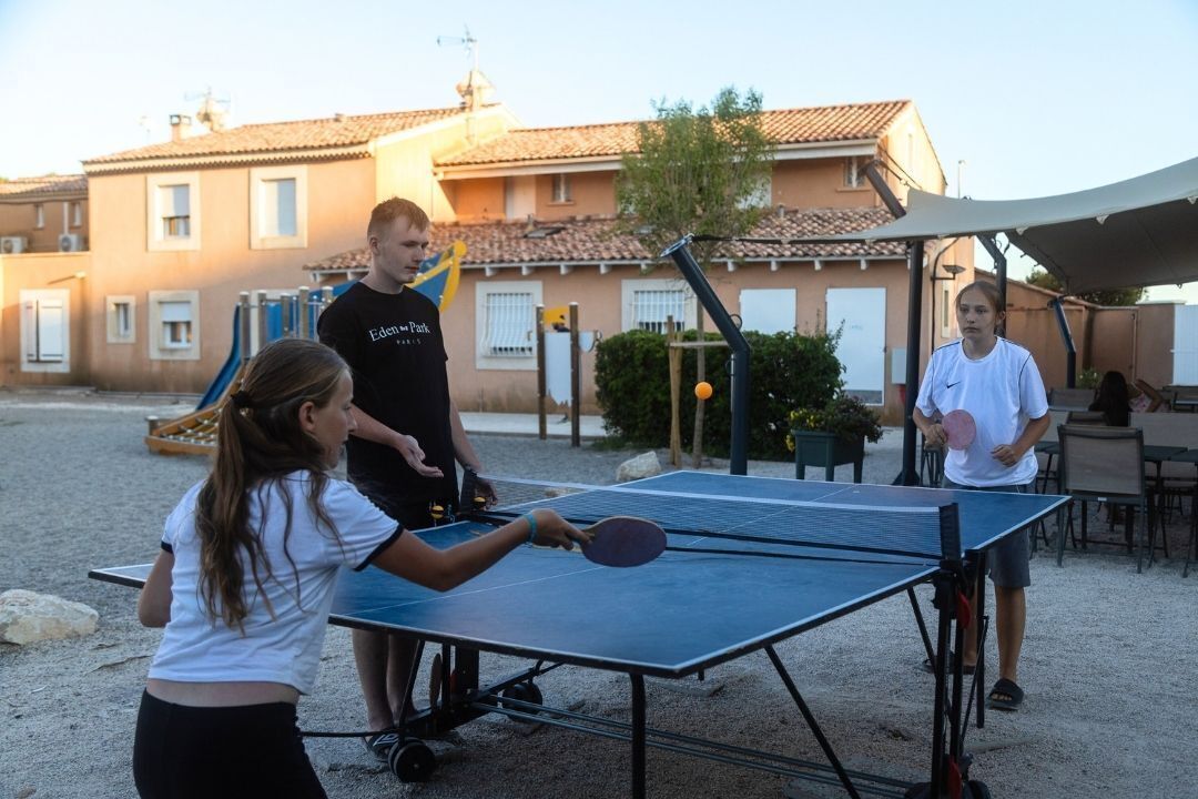 Mesa de tenis de mesa en un entorno exterior, con edificios al fondo.