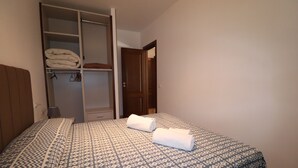 Een slaapkamer met een bed, een kledingkast en een deur naar een andere kamer.