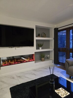 A modern living room with a flat-screen TV, a fireplace, and a sofa. - Nairn Nights (Nairn)