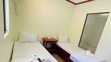 Een hotelkamer met twee éénpersoonsbedden, een klein tafeltje met een telefoon, en een spiegel aan de muur.
