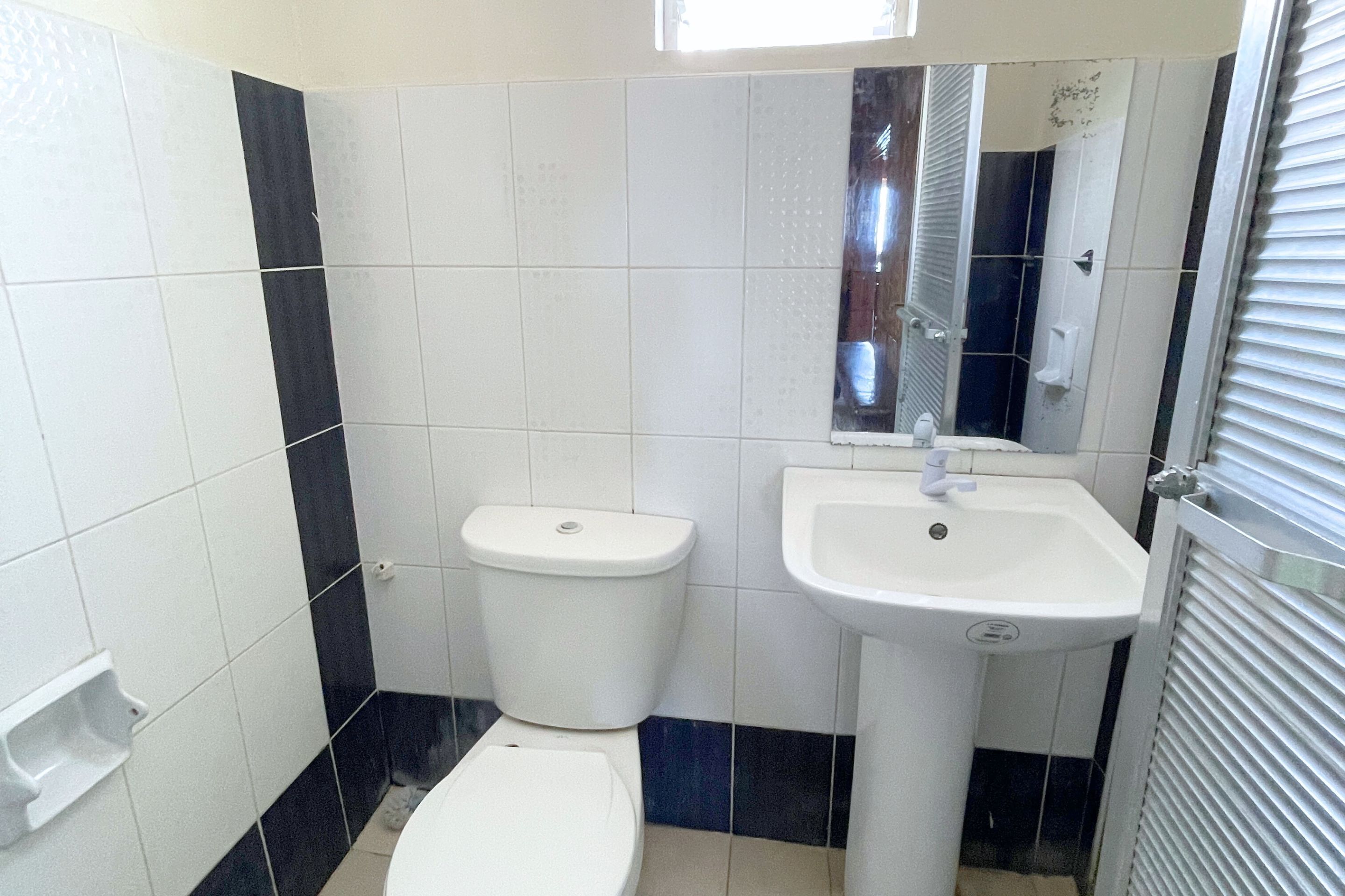 Un baño con inodoro, lavamanos y espejo.