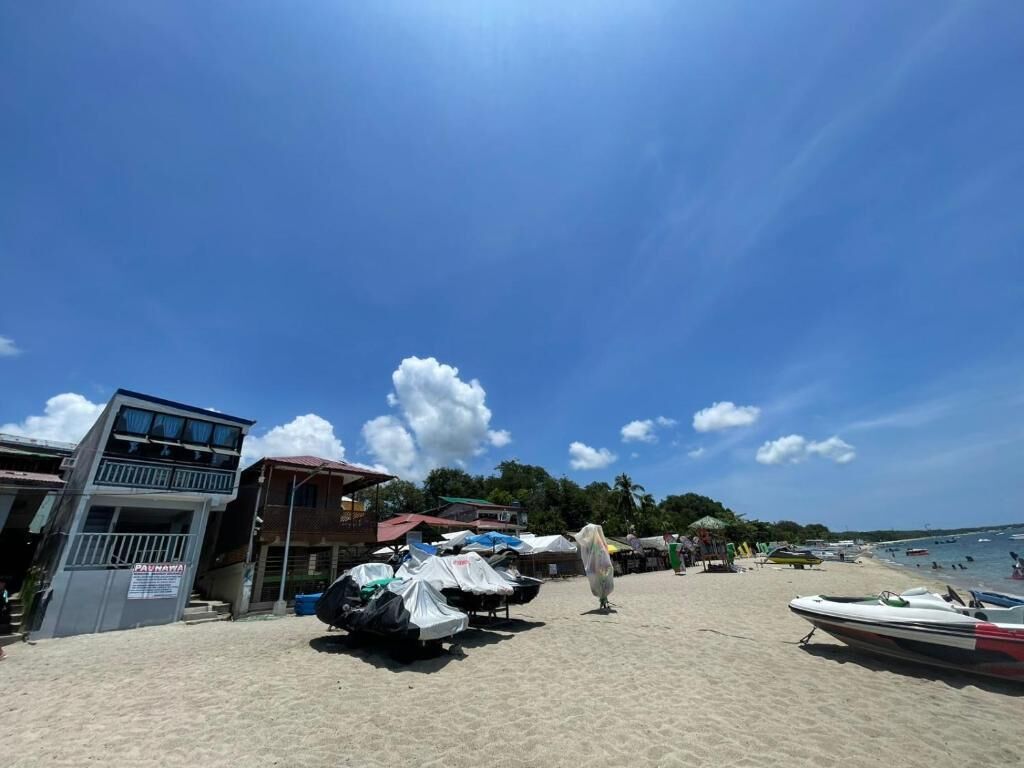 A beach with a building, covered vehicles, and a boat.