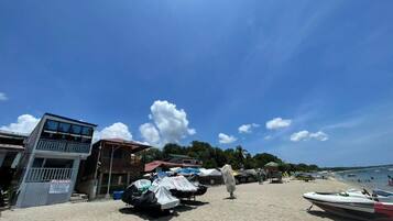 A beach with a building, covered vehicles, and a boat.