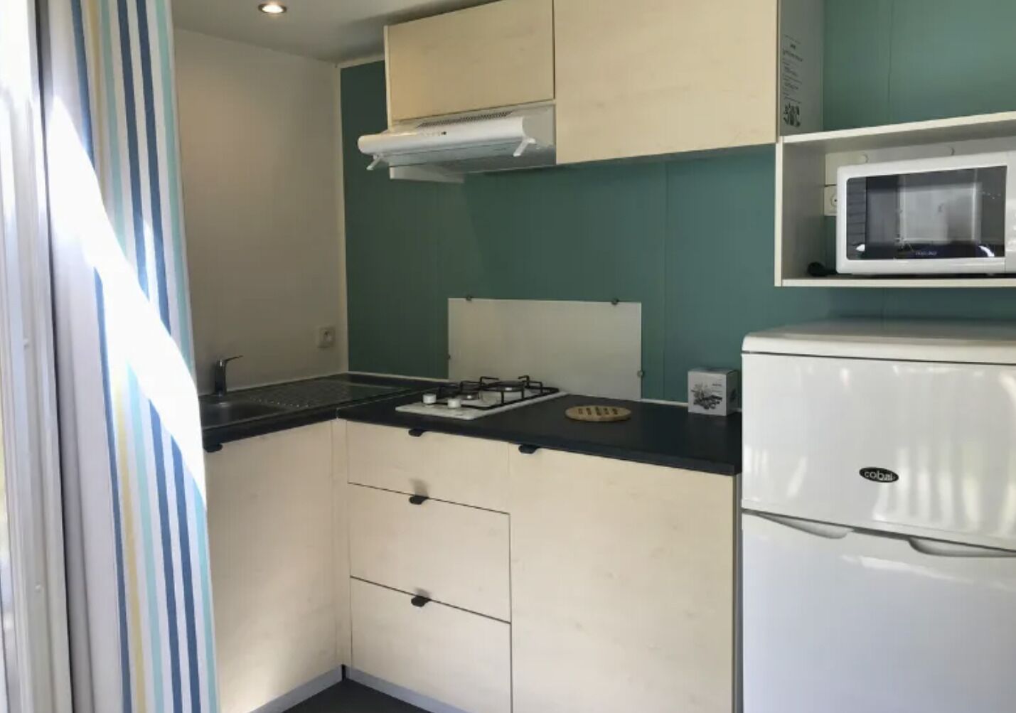 Een kleine keuken met een gasfornuis, een magnetron en een koelkast.