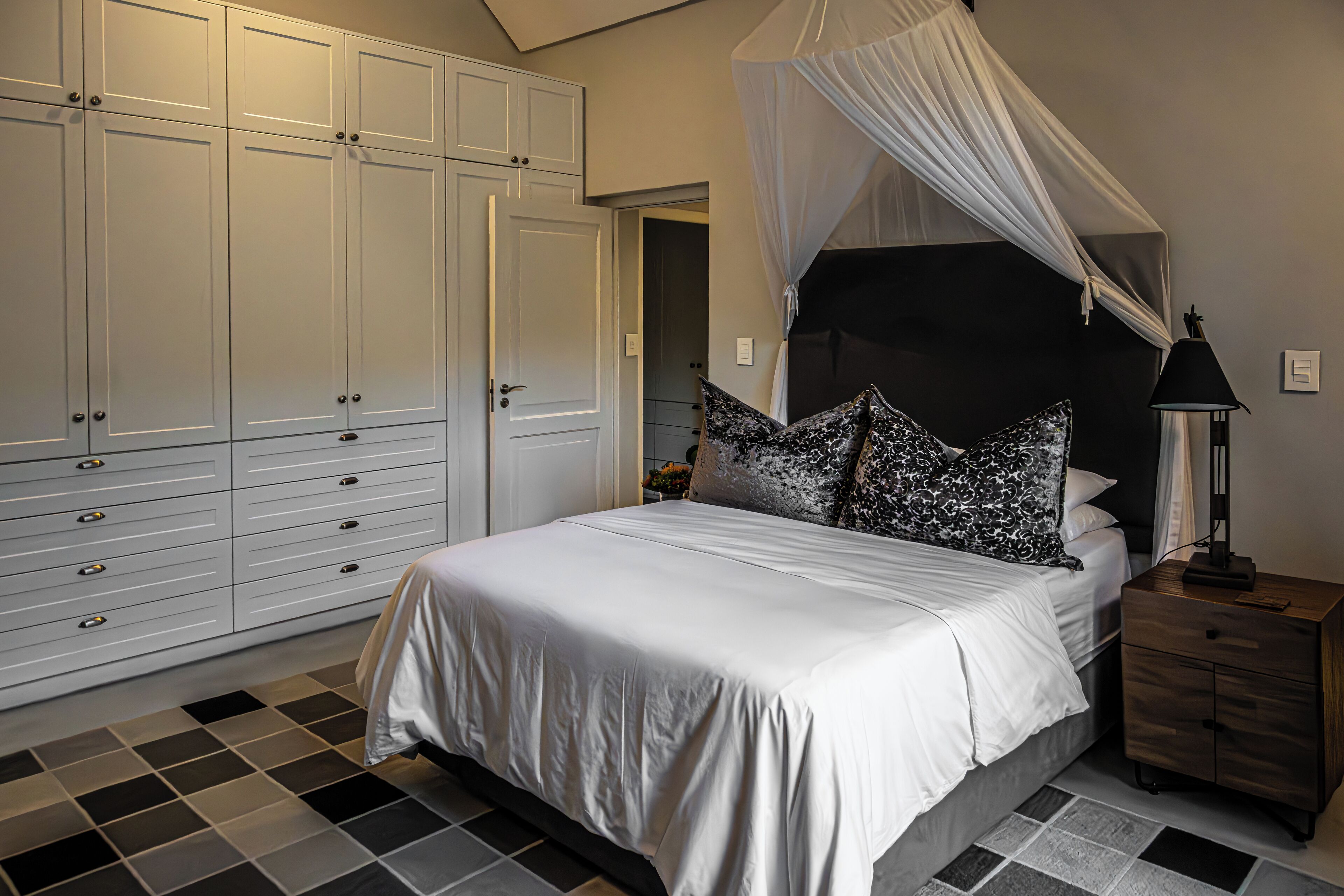 A bedroom with a bed, a nightstand, a wardrobe, and a canopy bed.
