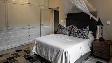 A bedroom with a bed, a nightstand, a wardrobe, and a canopy bed.