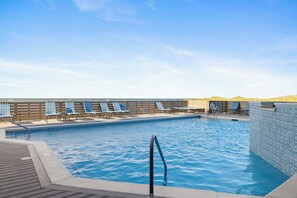 A swimming pool with lounge chairs and a wooden deck.