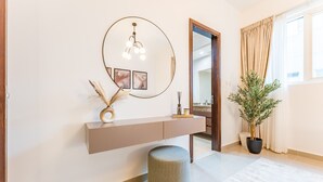 Een modern interieur met een ronde spiegel, een console tafel, een potplant en een rond poef.