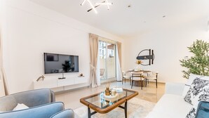 Een moderne woonkamer met een flatscreen televisie, een glazen salontafel en een bank.