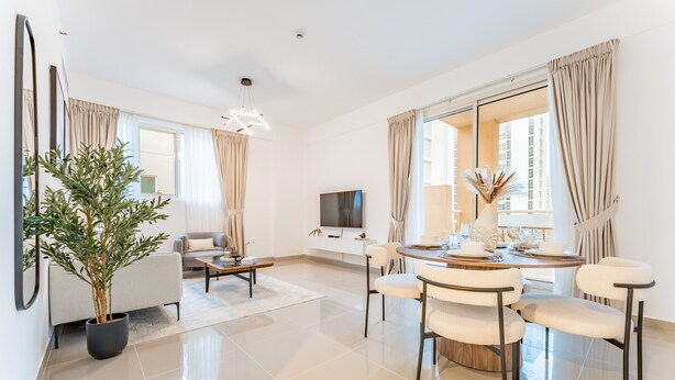 Een moderne woonkamer met een bank, salontafel, eettafel met stoelen, een potplant en een televisie.
