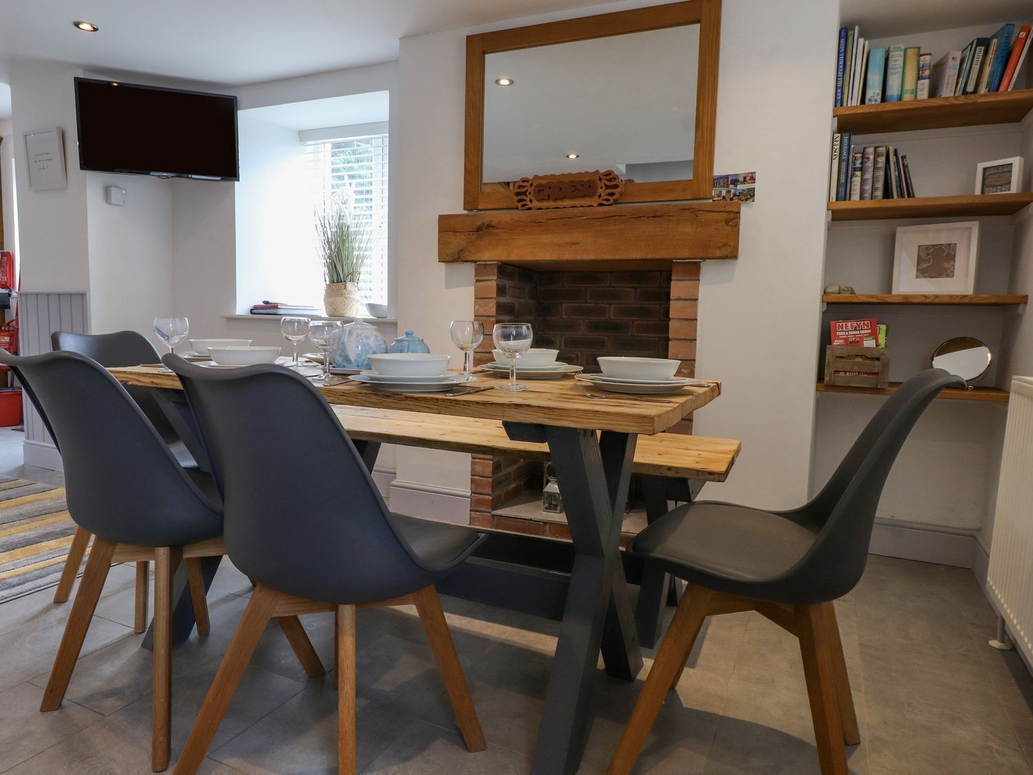 Un comedor con mesa de madera, sillas negras y chimenea de ladrillo.