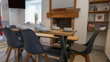Un comedor con mesa de madera, sillas negras y chimenea de ladrillo.