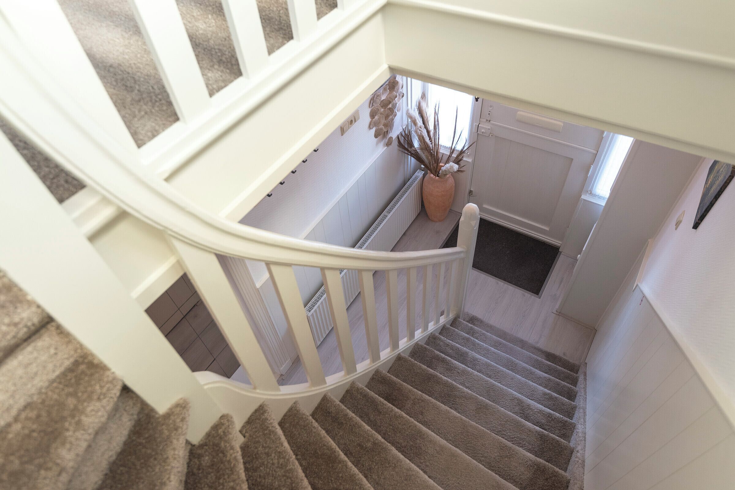 Eine Treppe mit weißer Handläufe und Teppichstufen.