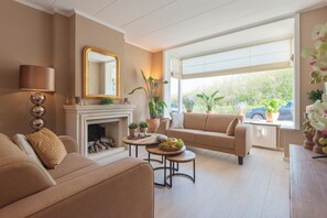 Sala de estar con chimenea, sofás color crema, una mesa de centro y un ventanal con vista a la vegetación.