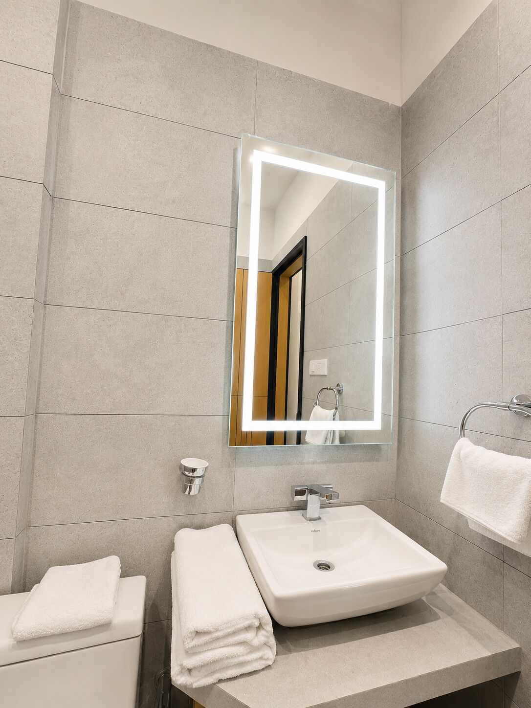 Une salle de bain moderne avec un grand miroir, un lavabo et un porte-serviettes.
