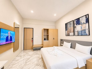 A hotel room with a bed, a TV, a wardrobe, and artwork on the wall. - Ixoras Hotel Lemba (Kinshasa)