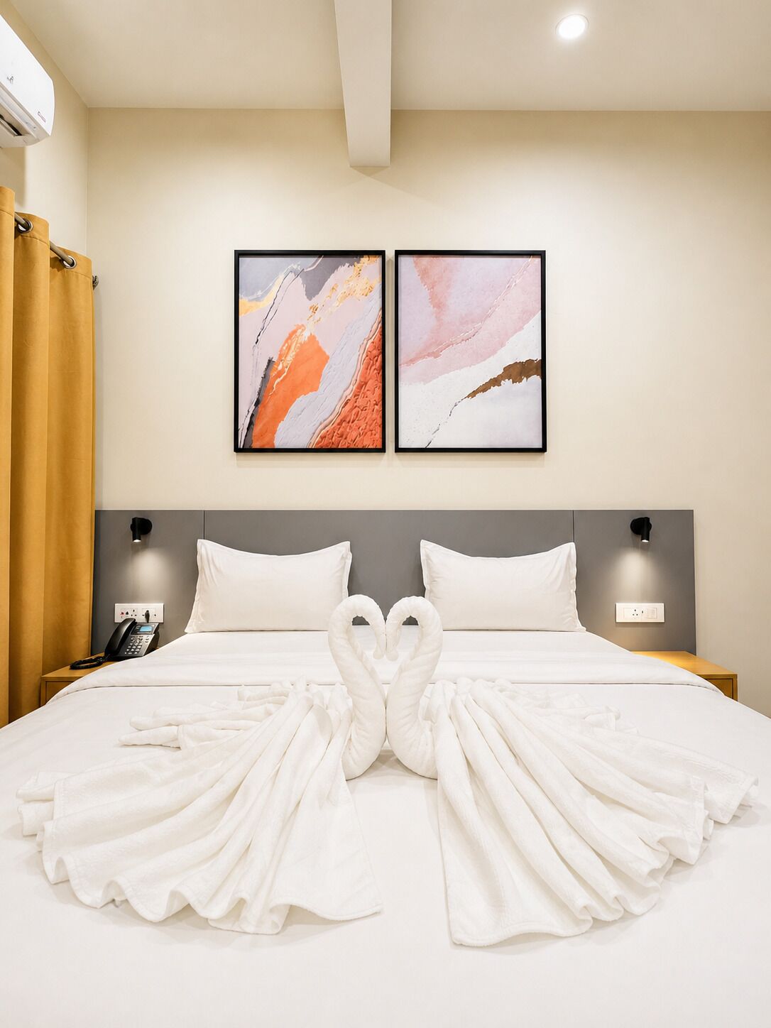 Camera d'albergo con un letto, due lampade a parete e due dipinti astratti.