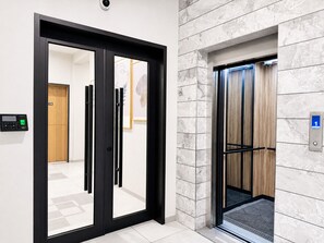 A modern elevator with a digital display, a wooden panel wall, and a floor number indicator. - Ixoras Hotel Lemba (Kinshasa)