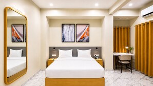 A hotel room with a large bed, bedside tables, a desk with a chair, and artwork on the walls. - Ixoras Hotel Lemba (Kinshasa)