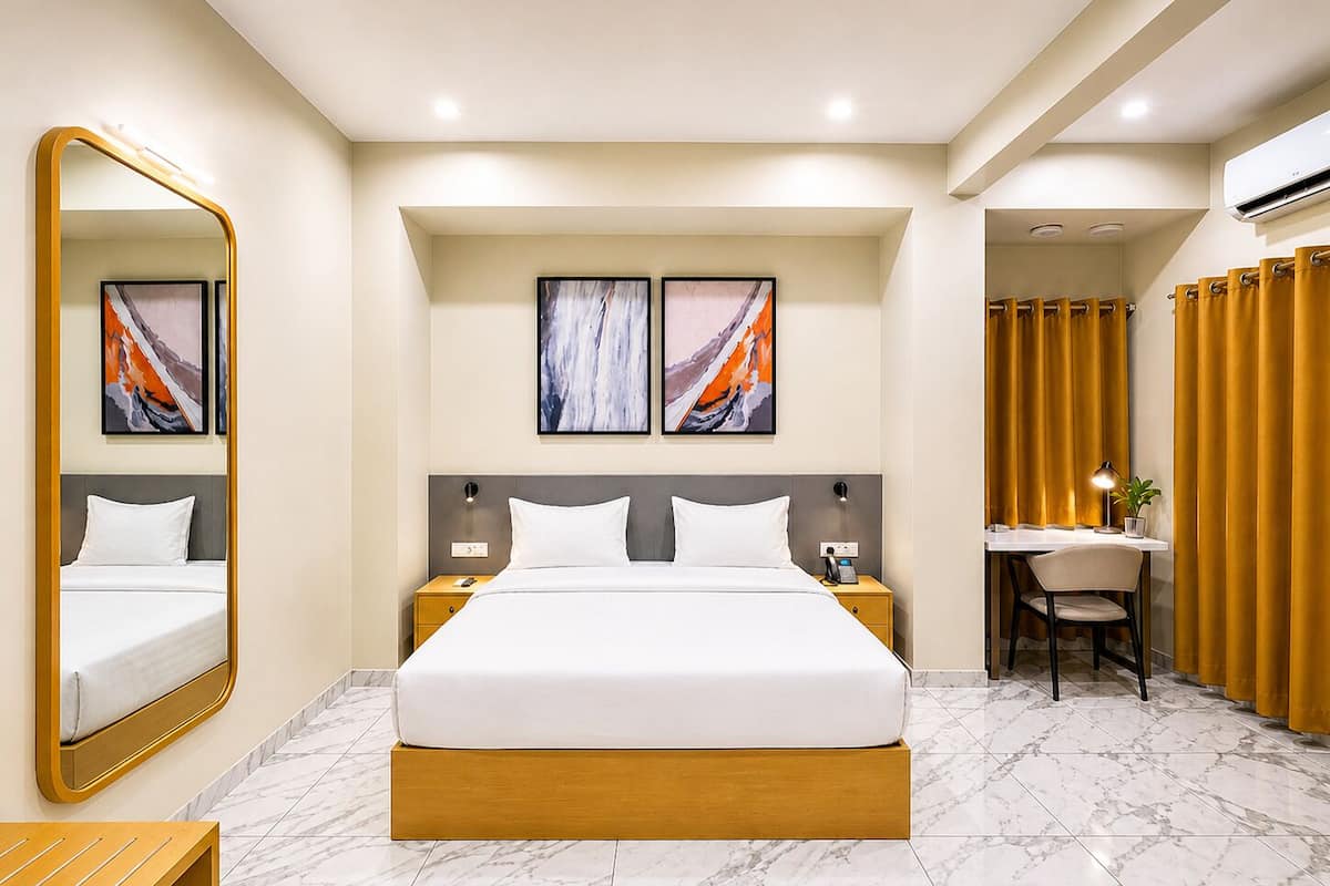 A hotel room with a large bed, bedside tables, a desk with a chair, and artwork on the walls.