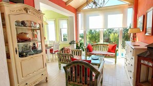 A spacious room with a large window, a wooden cabinet, and a dining area with chairs and a table. - Villa Avra - Private Garden Pool Oasis in Drama (Drama)