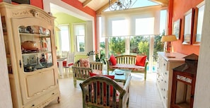 Une piĂšce spacieuse dotĂ©e dâune grande fenĂȘtre, dâun buffet en bois et dâun coin repas avec des chaises et une table.