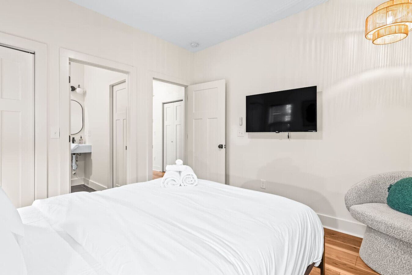 A hotel room with a large bed, a television mounted on the wall, and a chair with a cushion.