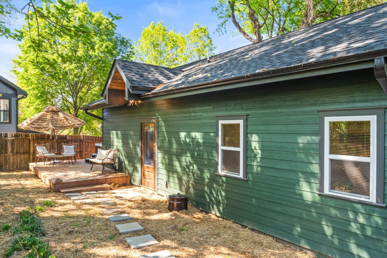 A green house with a porch, two windows, and a door.