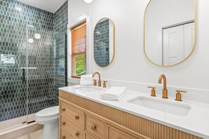 Ein modernes Badezimmer mit einem weißen Waschbecken, goldenen Armaturen und einem hölzernen Waschtisch.