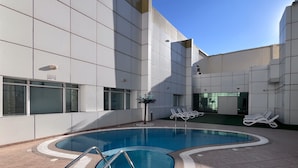 A modern indoor pool area with clear blue water, surrounded by white tiled walls and a glass window. - Manzil-1BR near JBR Beach & Blue Waters  (Dubai)