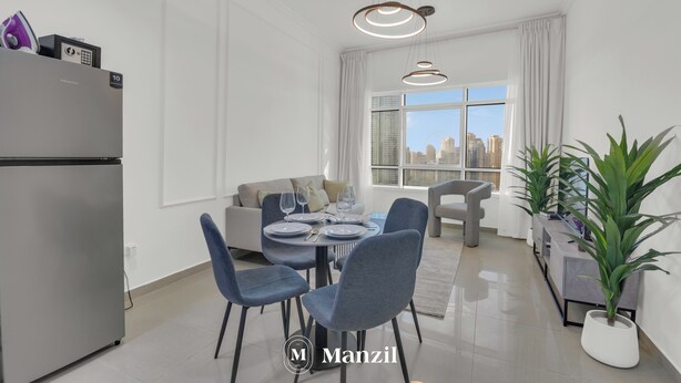 A modern kitchen with a refrigerator, dining table with chairs, and a view of the city through large windows. - Manzil-1BR near JBR Beach & Blue Waters  (Dubai)