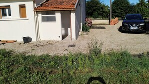 Una casa con tetto in tegole, vialetto sterrato e un'auto parcheggiata.