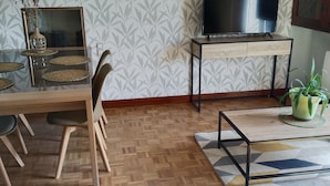 Zona pranzo con tavolo in legno, sedie, un vaso con piante essiccate e un grande specchio.