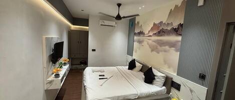 Una habitación de hotel moderna con una cama grande, un televisor, un escritorio y un aire acondicionado instalado en la pared.