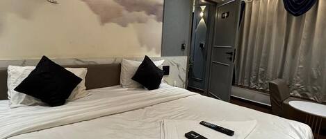 A hotel room with a large bed, a ceiling fan, and a mural of mountains and clouds on the wall.