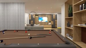 Een biljart met ballen, een bank, een televisie en een boekenplank in een moderne woonkamer.