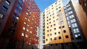Een meerlaags gebouw met een modern architectonisch ontwerp, met een combinatie van rode en gele gevels en veel ramen.