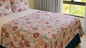 Une chambre à coucher avec un lit, une grande fenêtre avec des rideaux, un appareil de climatisation et un tableau encadr é au mur.