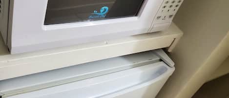 Un four à micro-ondes blanc doté d’un écran numérique et d’un panneau de commande, placé sur le dessus d’un réfrigérateur blanc.
