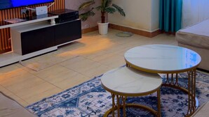 Un soggiorno moderno con una TV a schermo piatto, una pianta in vaso, un tavolino rotondo e un divano.