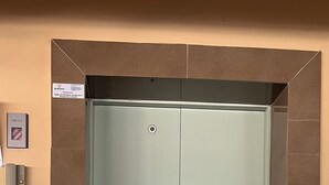 Porta chiusa dell'ascensore con un pannello di controllo sulla parete a sinistra.