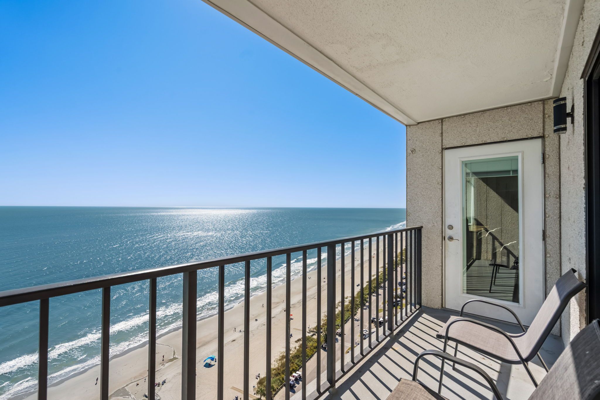 A balcony with a view of the beach and ocean.